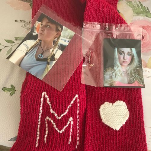 Photo of a young blonde woman lies on a red scarf embroidered. with the letter M and a white heart