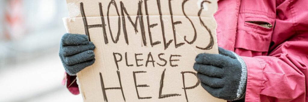 Closeup of a person holding a handwritten sign reading Homeless, please help