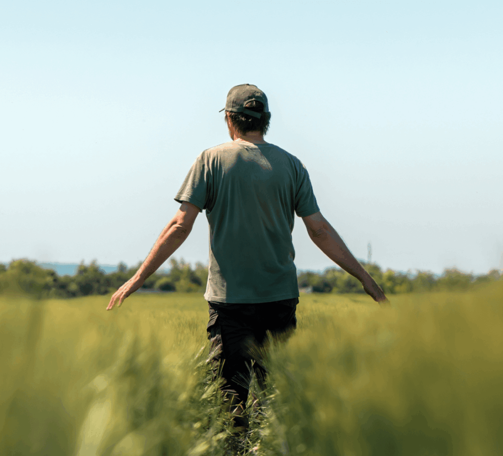 A man from behind walking through a field