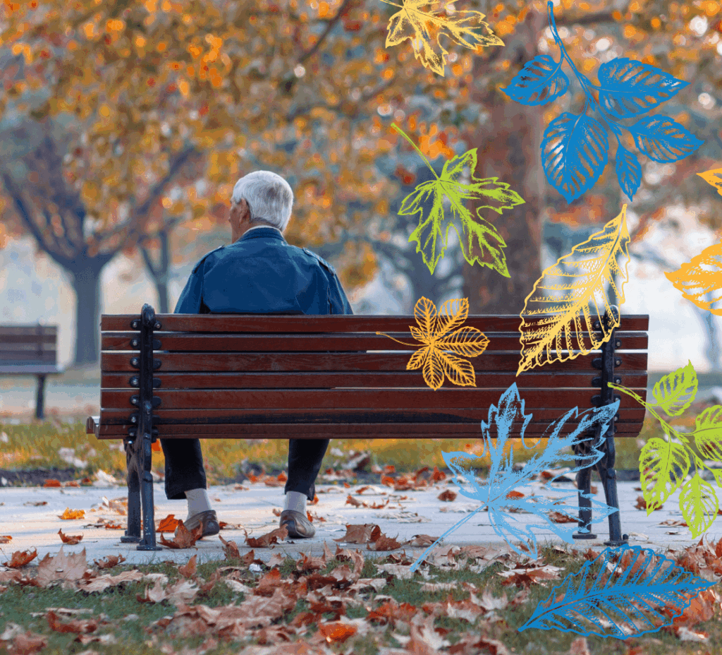 Older man sitting on a bench in the fall